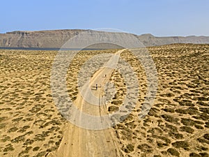 Aerial view of people cycling on a dirt path in the island of La Graciosa, Lanzarote, Canary Islands. Spain.