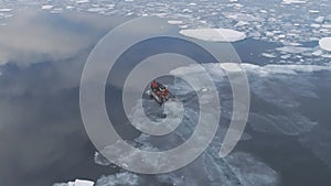 Aerial view of people in expedition boat sail in brash ice water.