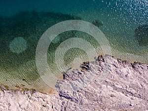 Aerial view of people moving among the rocks in the sea. Overview of the seabed seen from above, transparent water.