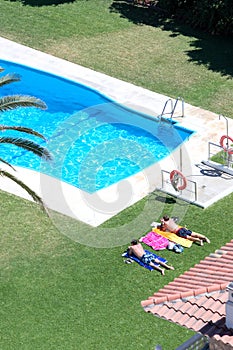Aerial view of people sunbathing by a pool