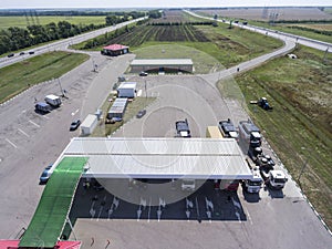 Aerial view at petrol station with trucks, passenger cars filling gas, it is located between two highways, plain terrain