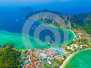 Aerial view of Phi Phi, Maya beach with blue turquoise seawater, mountain hills, and tropical green forest trees at sunset with