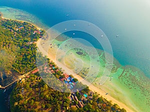 Aerial view of Phi Phi, Maya beach with blue turquoise seawater, mountain hills, and tropical green forest trees at sunset with