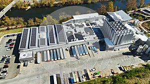 Aerial view of photovoltaic solar panels mounted on industrial building roof for producing green ecological electricity