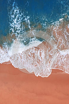 Aerial view of pink beach and blue ocean wave.