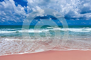 Aerial view of pink beach and blue ocean wave.