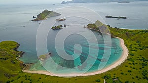 Aerial view of Pink Beach with green color on the hill and turquoise sea from Komodo Island Labuan Bajo