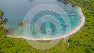 Aerial view of Pink Beach with green color on the hill and turquoise sea from Komodo Island Labuan Bajo