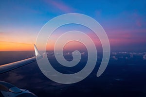 Aerial view from the plane on colorful sky before sunrise. Part of wing aircraft and turbine. Soft selective focus