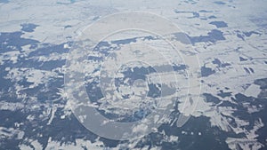 Aerial view from the plane on snowy winter fields and clouds