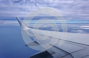 Aerial view of plane window above clouds under blue sky. View from aircraft window. Airline, business photo