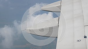 Aerial view through plane window with view of airplane wing over puffy white cloud with clear blue sky while flying, View from the