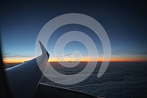 Aerial view of plane wing in sunrise during flight