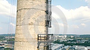 Aerial view A power plant engineer climbs a high chimney. Maintenance of industrial chimneys by a power plant employee