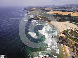 Aerial view of Praia de Odeceixe with people on the beach in summertime with Atlantic Ocean rough sea in background, Odeceixe,