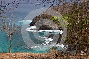 Aerial view of Praia do Sancho beach with steep cliffs and foamy waves in Pernambuco, Brazil