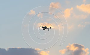 Aerial view of a professional drone with propellers flying with camera with sunset sky in digital technology concept. An
