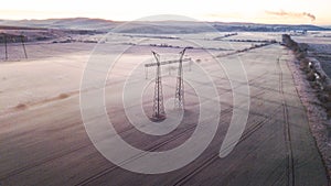 Aerial view pylons with electric wires that are located in the field