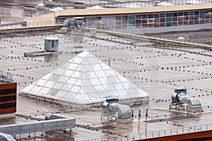 Aerial view pyramid-shaped skylight window flat roof with air conditioners top modern apartment building. Urban