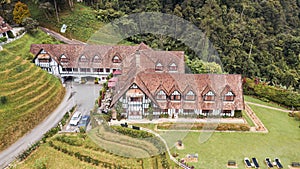 Aerial view of a quaint cottage nestled in the rolling hills of Cameron Highlands, Malaysia.