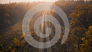 Aerial view of railroad in forest in fog at sunrise in autumn