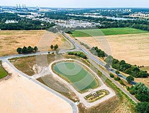 Aerial view of a rain retention basin at the edge of a new development, taken oblique