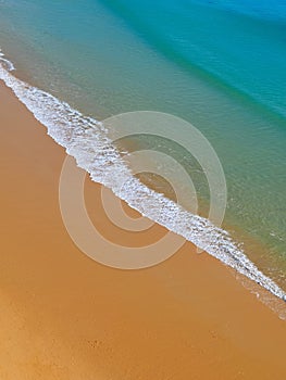 Aerial view of red beach sand with blue ocean and waves