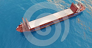 Aerial view. Red deck cargo ship sailing on open sea.