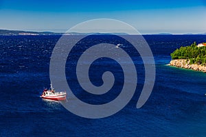 Aerial view of red fishing boat on a deep blue sea in Greece.