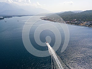 Aerial view of a red motor boat speeds by in the Kotor fjord in Montenegro.