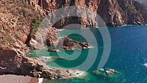 Aerial view of red rock cliffs mountain, sand beach, waves crushing on the beach. Colored sea, blue turquoise, high red