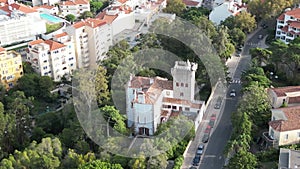 Aerial view of red roof buildings, a street with cars and trees in Monte Estoril, Portugal.