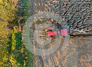 Aerial view of red tractor plowing field in autumn