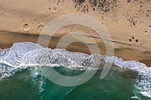 Aerial view of a remote sandy beach and sea waves