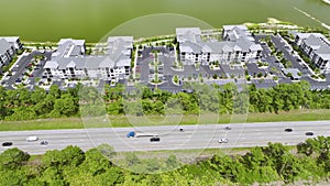 Aerial view of residential apartment buildings near busy american highway with heavy fast moving traffic. Interstate