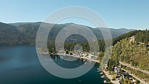 Aerial view of a residential homes by a lake and mountains.