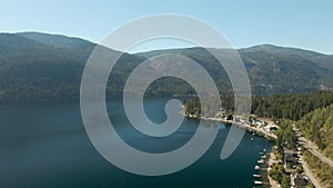 Aerial view of a residential homes by a lake and mountains.