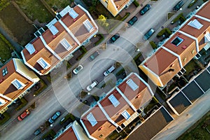 Aerial view of residential houses with red roofs and streets with parked cars in rural town area. Quiet suburbs of a modern