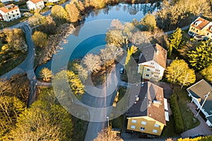 Aerial view of residential houses with red roofs and streets with parked cars in rural town area. Quiet suburbs of a modern