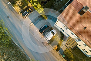 Aerial view of residential houses with red roofs and streets with parked cars in rural town area. Quiet suburbs of a modern