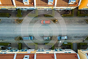 Aerial view of residential houses with red roofs and streets with parked cars in rural town area. Quiet suburbs of a modern