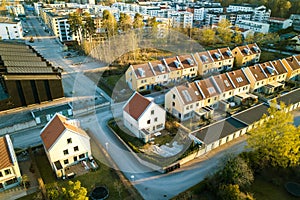 Aerial view of residential houses with red roofs and streets with parked cars in rural town area. Quiet suburbs of a modern