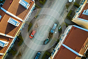 Aerial view of residential houses with red roofs and streets with parked cars in rural town area. Quiet suburbs of a modern