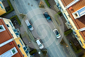 Aerial view of residential houses with red roofs and streets with parked cars in rural town area. Quiet suburbs of a modern