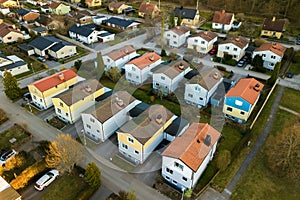 Aerial view of residential houses with red roofs and streets with parked cars in rural town area. Quiet suburbs of a modern