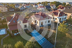 Aerial view of a residential private house with solar panels on roof and wind generator turbine