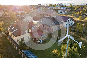 Aerial view of a residential private house with solar panels on roof and wind generator turbine