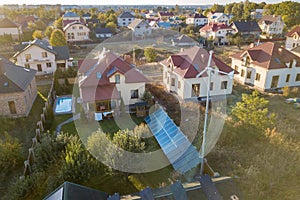 Aerial view of a residential private house with solar panels on roof and wind generator turbine