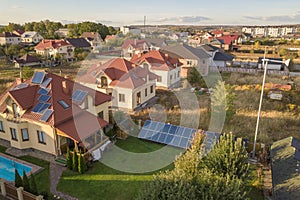 Aerial view of a residential private house with solar panels on roof and wind generator turbine