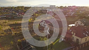 Aerial view of a residential private house with solar panels on roof and wind generator turbine.